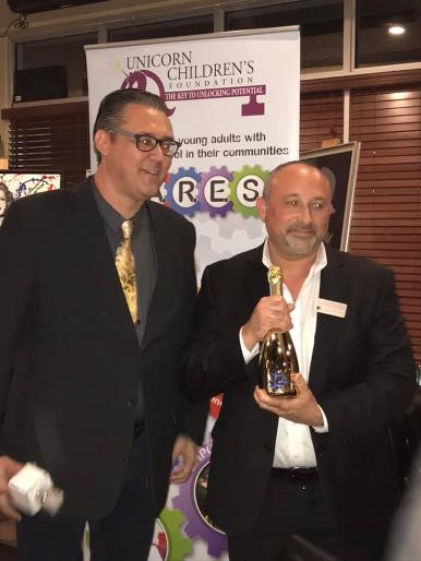 Jay Shapiro and door prize winner William Gerstein wins a bottle of Lamborgini Champagne at a Luxury Chamber of Commerce and Unicorn Childrens Foundation Networking Event, Temper Grille in Boca Raton, FL