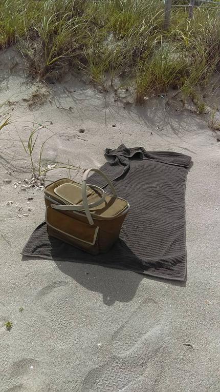 foosteeps in the sand, towel and picnic basket on florida beach